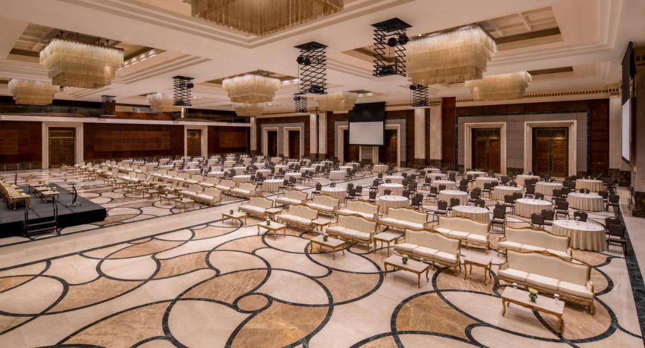 Makkah Clock Royal Tower, A Fairmont Hotel La La Mecca Esterno foto The photo shows an elegant conference or banquet hall. The room features rows of beige and gold chairs arranged around tables, likely covered in white tablecloths. The flooring has a decorative pattern, and the walls are adorned with dark wood accent