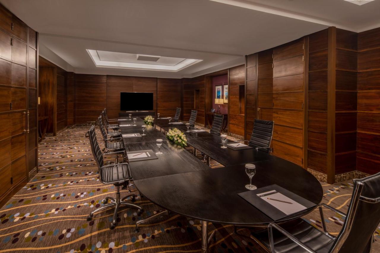 Makkah Clock Royal Tower, A Fairmont Hotel La La Mecca Esterno foto The photo depicts a modern conference room designed for meetings and presentations. It features a large, oval table surrounded by ergonomic chairs. The room has a warm, wooden paneling on the walls and a textured carpet with various patterns. A telev