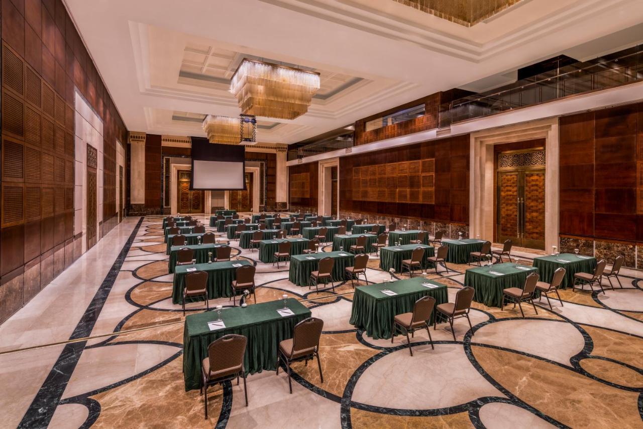 Makkah Clock Royal Tower, A Fairmont Hotel La La Mecca Esterno foto The photo shows a large conference room or meeting space. The room features polished marble flooring with a decorative pattern. There are several rectangular tables covered with green tablecloths arranged neatly throughout the space, each paired with