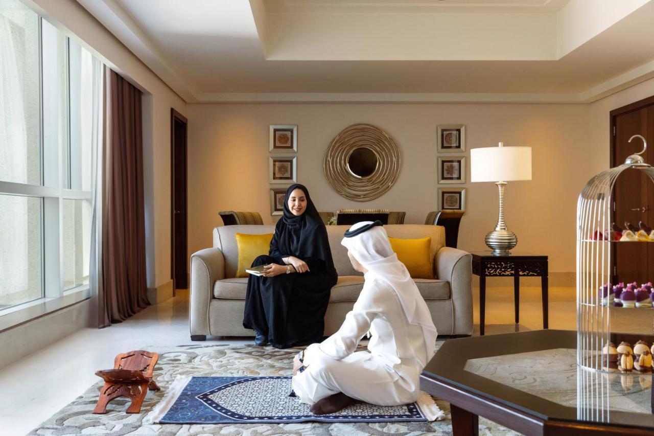 Makkah Clock Royal Tower, A Fairmont Hotel La La Mecca Esterno foto The photo depicts a modern and elegantly designed living room. In the foreground, two individuals are engaged in conversation. One is wearing a traditional Emirati outfit, while the other is dressed in a black abaya. The room features large windows w