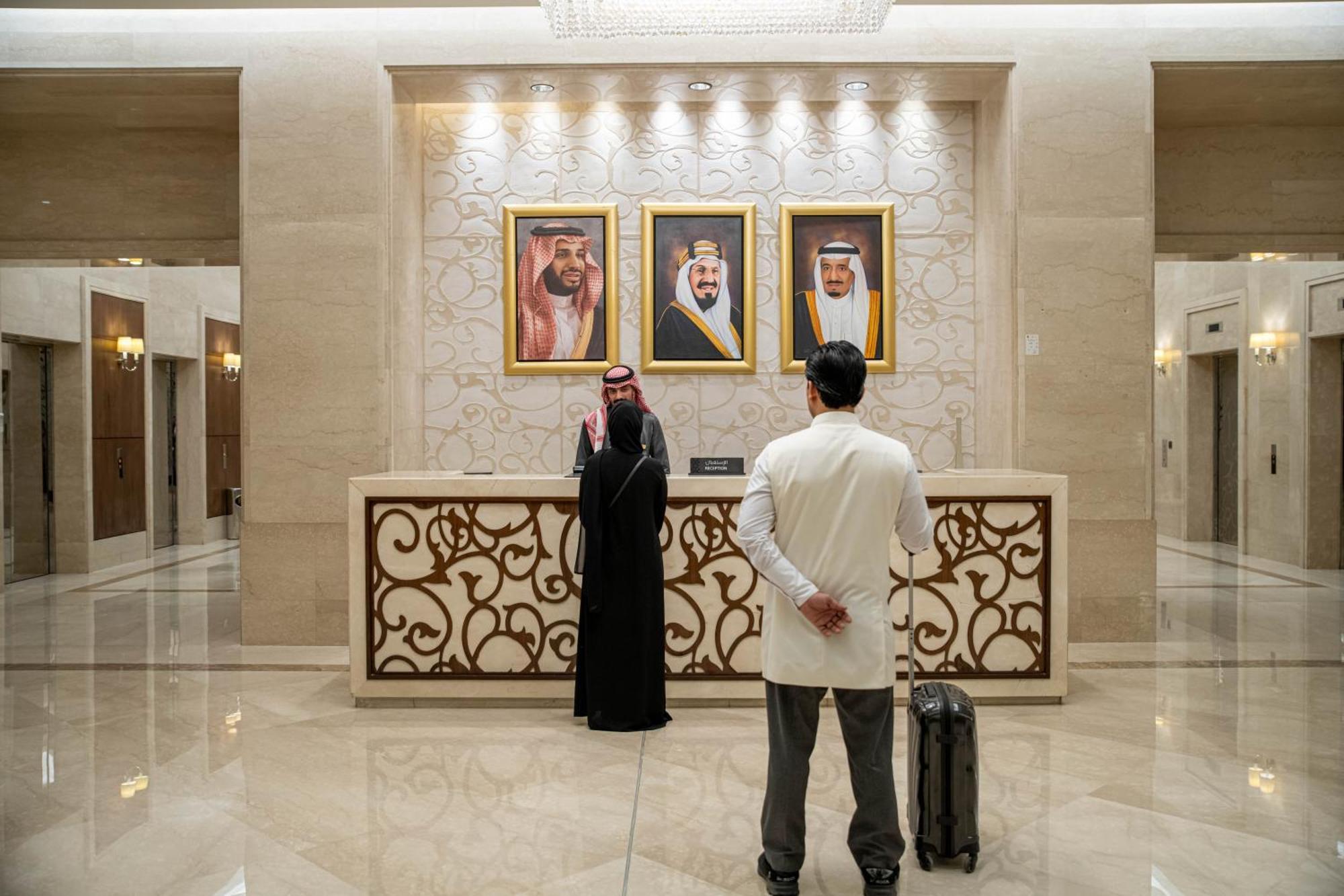 Makkah Clock Royal Tower, A Fairmont Hotel La La Mecca Esterno foto The photo shows a luxurious hotel lobby with a modern design. In the background, there are three framed portraits hanging on the wall, likely depicting influential leaders. In the foreground, two men are present: one is wearing traditional attire, wh