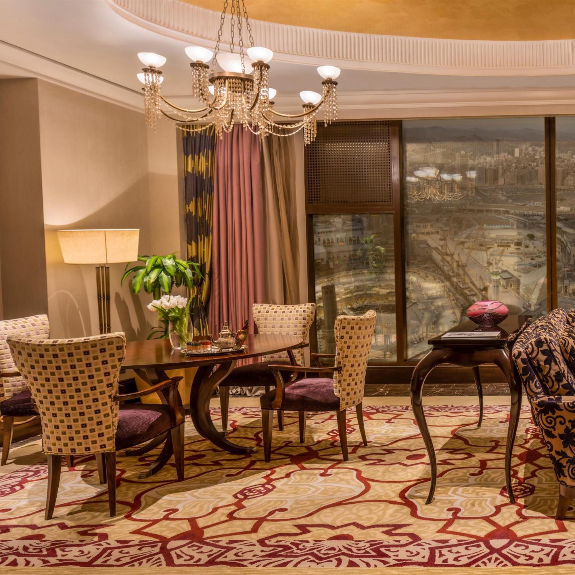 Makkah Clock Royal Tower, A Fairmont Hotel La La Mecca Esterno foto The photo depicts a luxurious interior space, likely a living or dining area. It features elegant furniture, including a round dining table surrounded by patterned chairs. A lavish chandelier hangs from the ceiling, adding a touch of sophistication. 