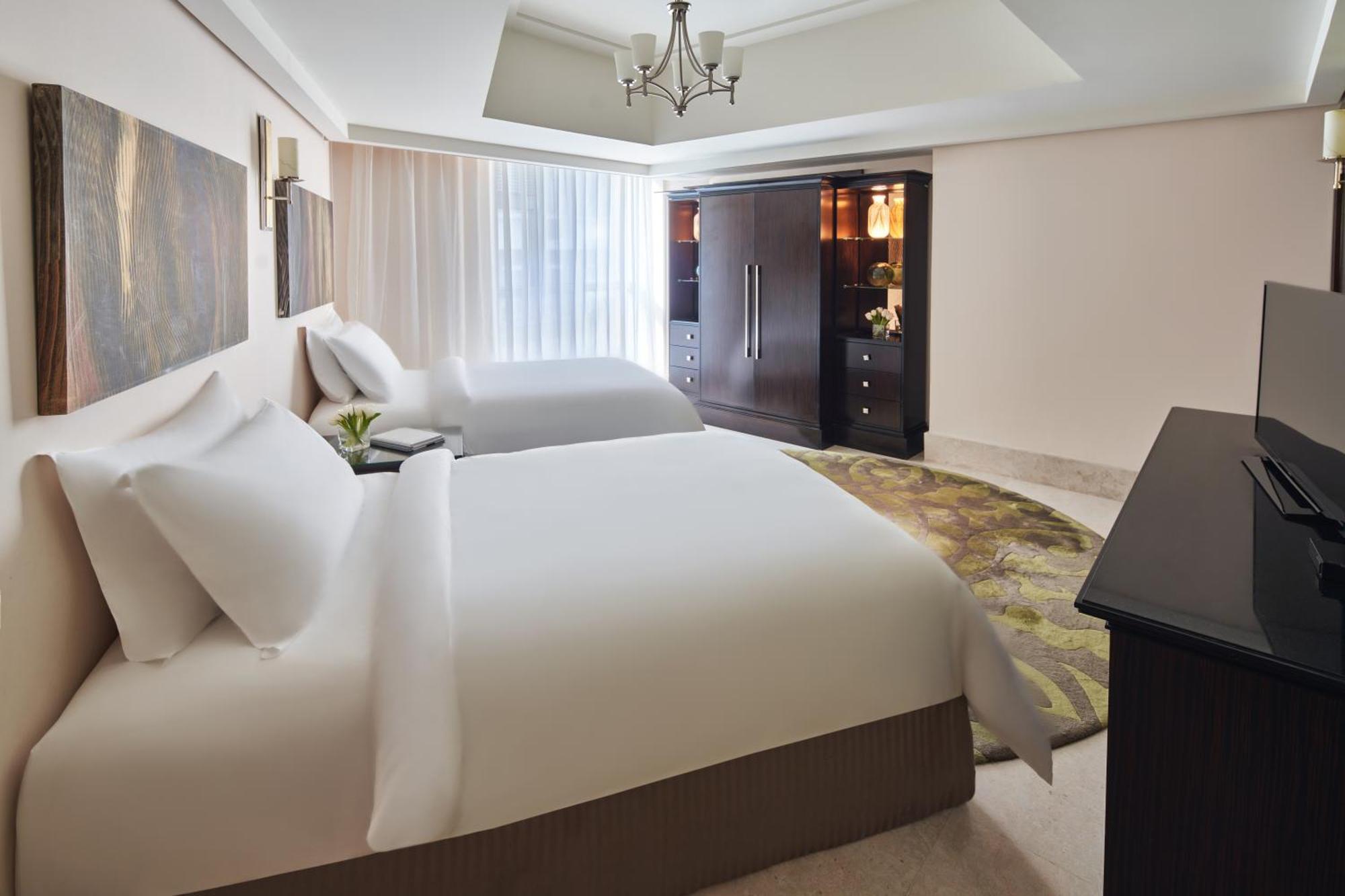 Makkah Clock Royal Tower, A Fairmont Hotel La La Mecca Esterno foto The photo shows a hotel room featuring two neatly made beds with crisp white bedding. There's a large window with sheer curtains allowing natural light to enter the space. A decorative piece of art hangs on the wall above the beds, and the floor is p