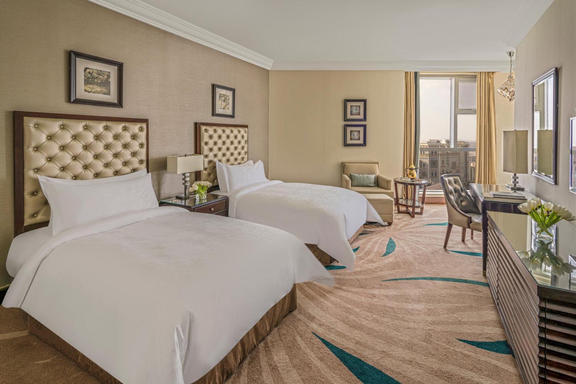 Makkah Clock Royal Tower, A Fairmont Hotel La La Mecca Esterno foto The photo showcases a well-appointed hotel room featuring two beds with tufted headboards. The beds are made up with white linens and fluffy pillows. There are two bedside tables with lamps next to each bed. A comfortable armchair is positioned near 