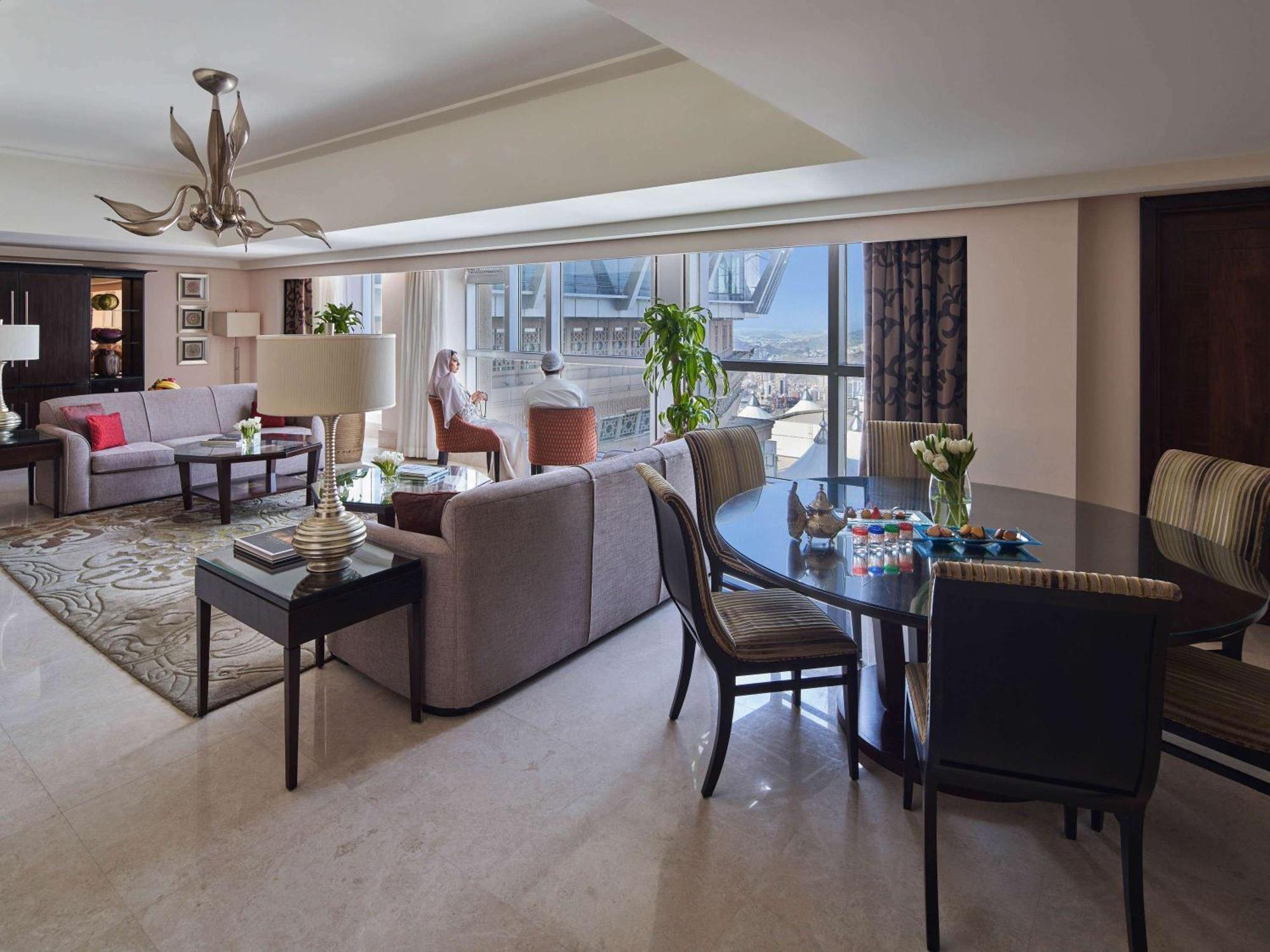 Makkah Clock Royal Tower, A Fairmont Hotel La La Mecca Esterno foto The photo shows a well-furnished living room and dining area. The space features modern, comfortable furniture including two sofas in neutral colors and a dining table with chairs. The room has large windows allowing natural light to fill the space, 