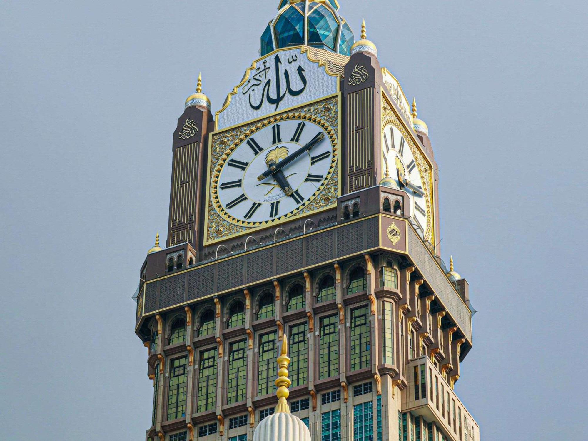 Makkah Clock Royal Tower, A Fairmont Hotel La La Mecca Esterno foto The photo shows a large clock tower, which is part of a prominent building. The tower features a distinctive clock face with large numbers and hands, indicating the time. At the top of the tower, there is an ornate dome covered with blue tiles. The b